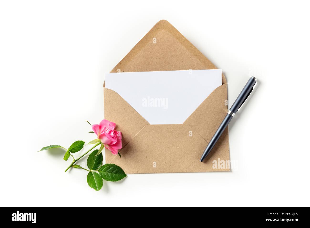 Invito o biglietto d'auguri mockup in una busta marrone kraft, girato dall'alto su uno sfondo bianco con una rosa rosa e una penna Foto Stock