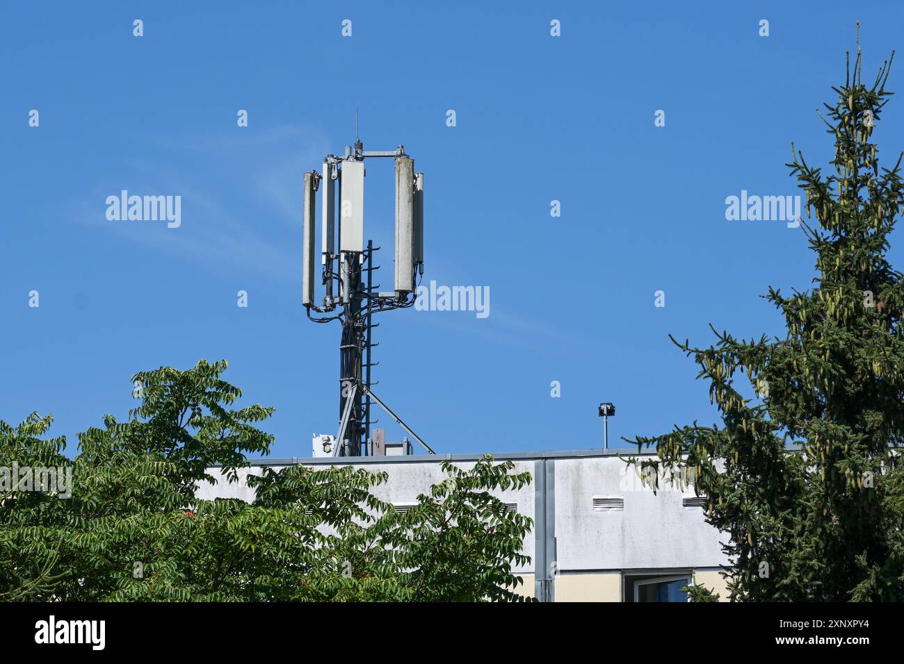 Antenna della stazione base della rete cellulare sul montante di telecomunicazione per la comunicazione mobile sul tetto di un condominio contro un sk blu Foto Stock