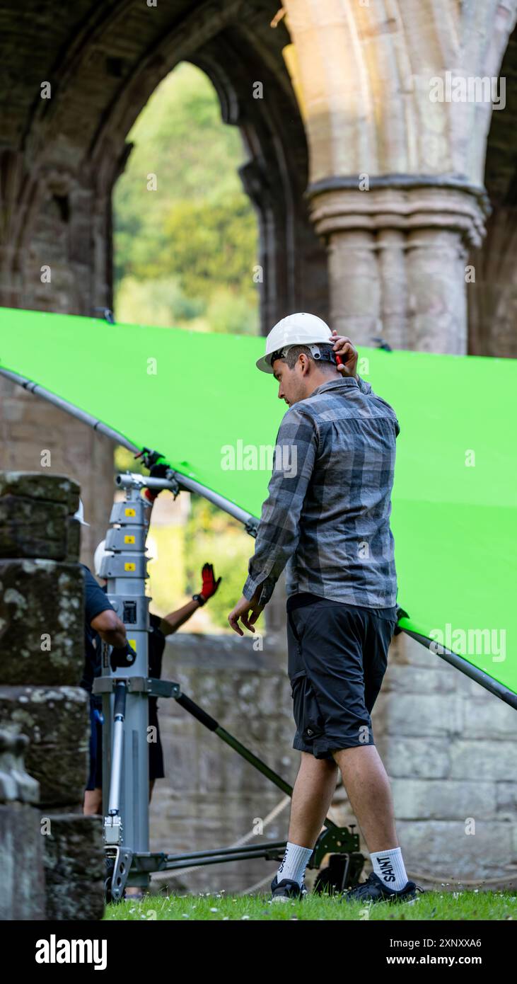 Dietro le quinte di un set cinematografico con la troupe che imposta uno schermo verde per un effetto cromatico Foto Stock