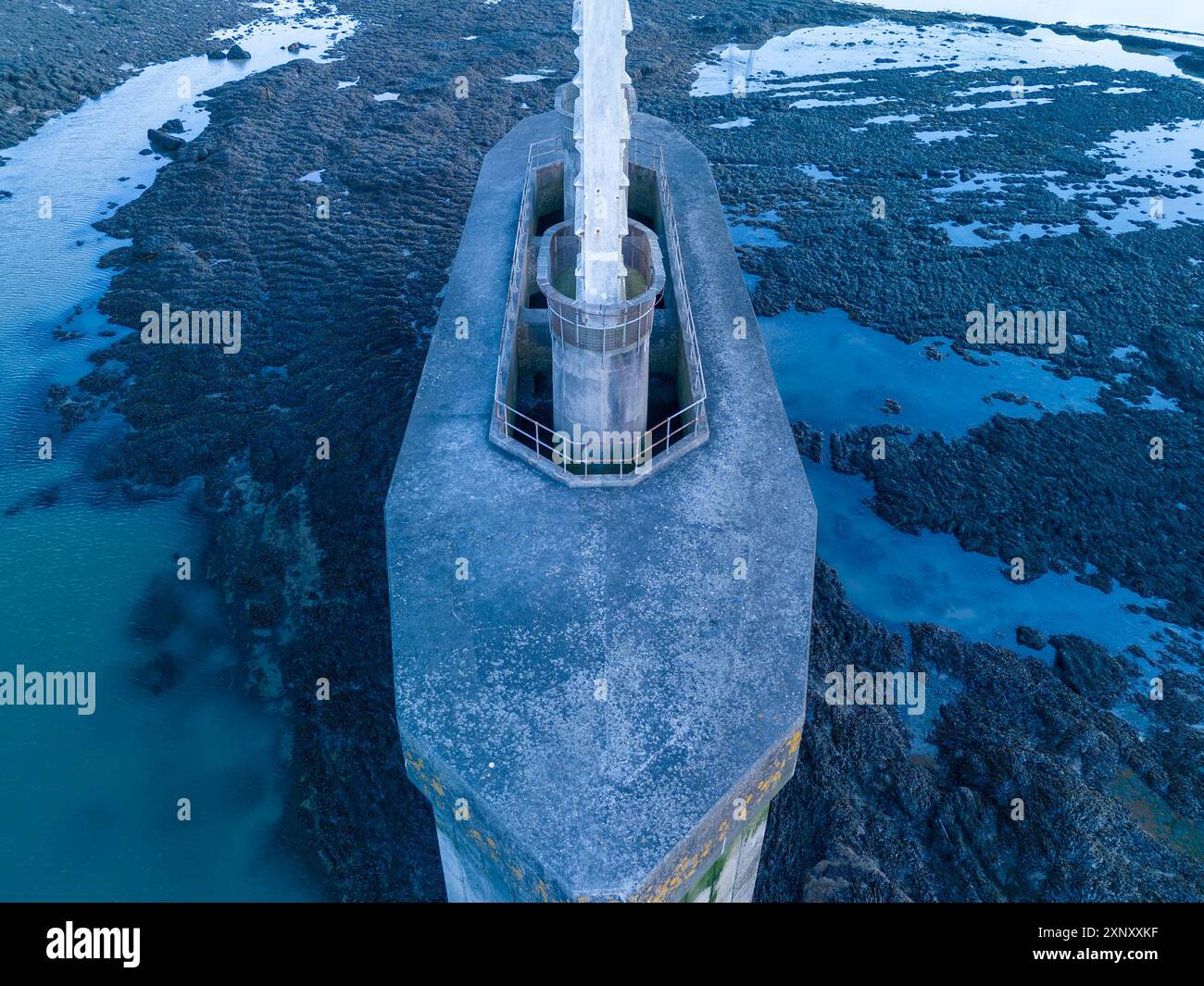 Vista aerea di un vecchio faro costruito su rocce nel mezzo di un oceano blu Foto Stock