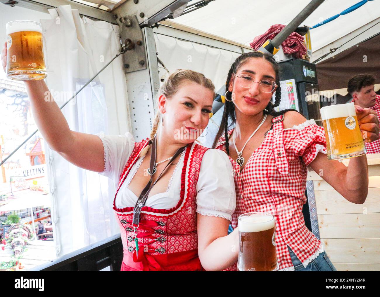 Herne, NRW, Germania. 2 agosto 2024. Due cameriere servono con un sorriso. Cranger Kirmes, la seconda fiera più grande della Germania (dopo l'Oktoberfest di Monaco), si apre con la tradizionale spillatura del barile, effettuata dal sindaco Frank Dudda, dal vice PM dell'NRW Mona Neubaur e da altri, oltre all'intrattenimento della cantante tedesca Vanessa mai. La vivace fiera ha una lunga tradizione che risale al XV secolo, dove un mercato di cavalli e successivamente intrattenitori medievali, legnavano la folla. Cranger Kirmes attrae circa 4 milioni di visitatori ogni anno in un sito dedicato lungo il canale Reno-Herne. Foto Stock
