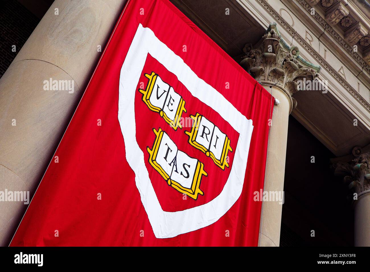 Cambridge, Massachusetts, USA - 24 giugno 2022: Primo piano del logo dell'Università di Harvard su uno striscione rosso appeso a un edificio. Il logo è uno scudo W. Foto Stock