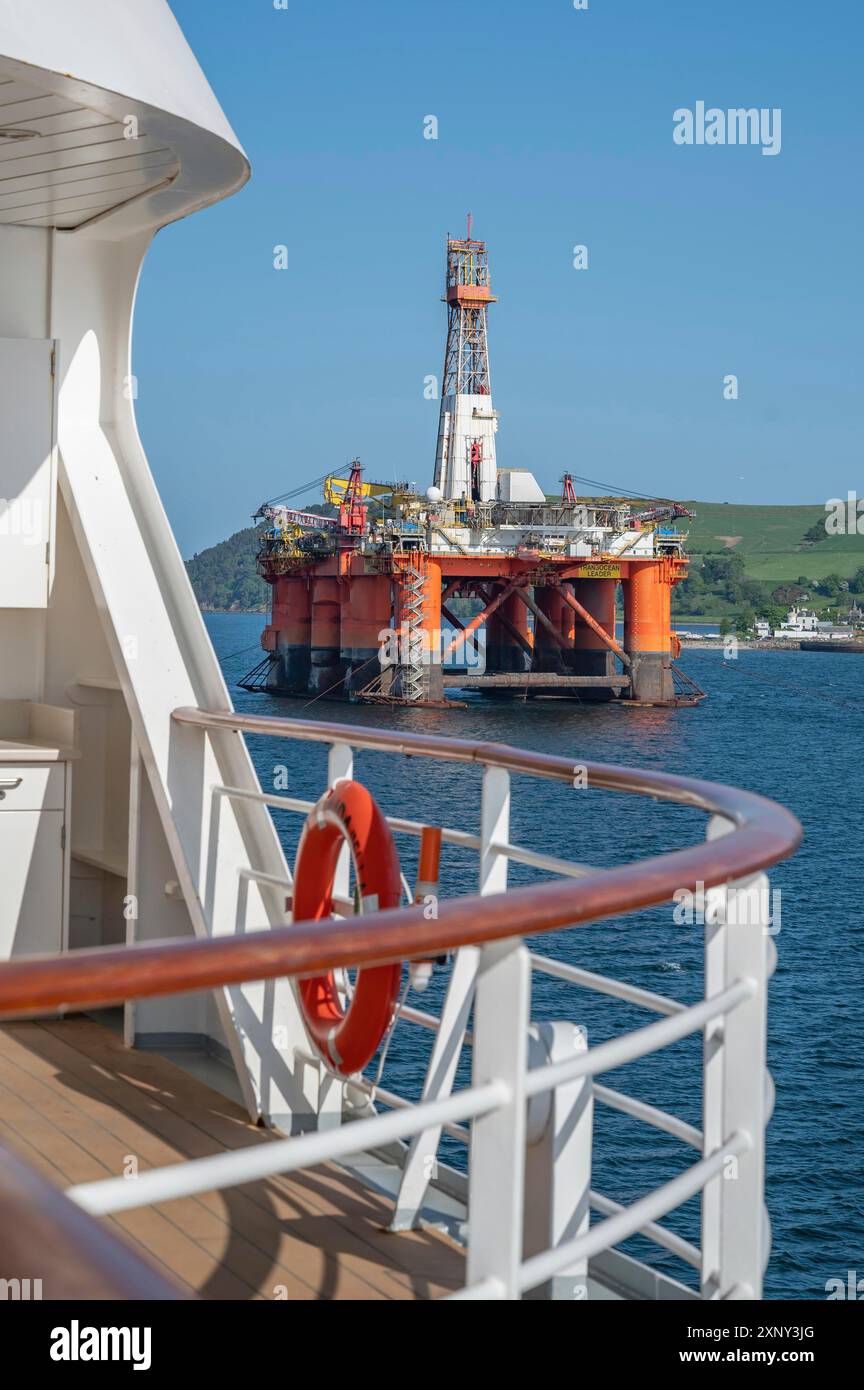 Piattaforma petrolifera Transocean leader con nave da crociera di fronte a Invergordon in cielo limpido, colpo verticale Foto Stock