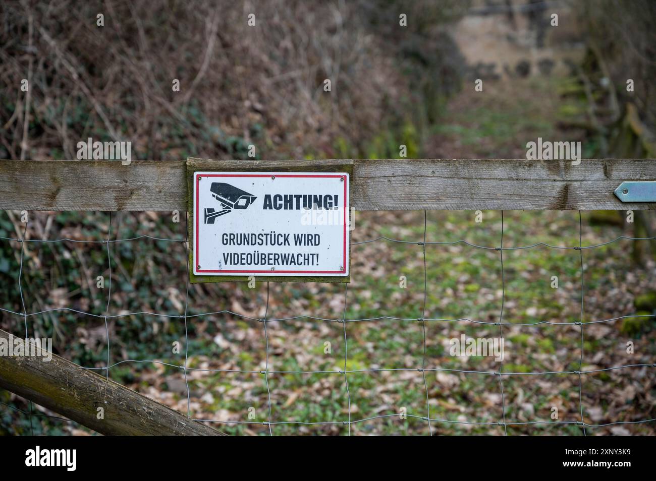 Achtung Grundstueck wird Videoueberwacht si prega di notare che la proprietà è sotto videosorveglianza cartello attaccato ad una recinzione di legno con giardino nel Foto Stock