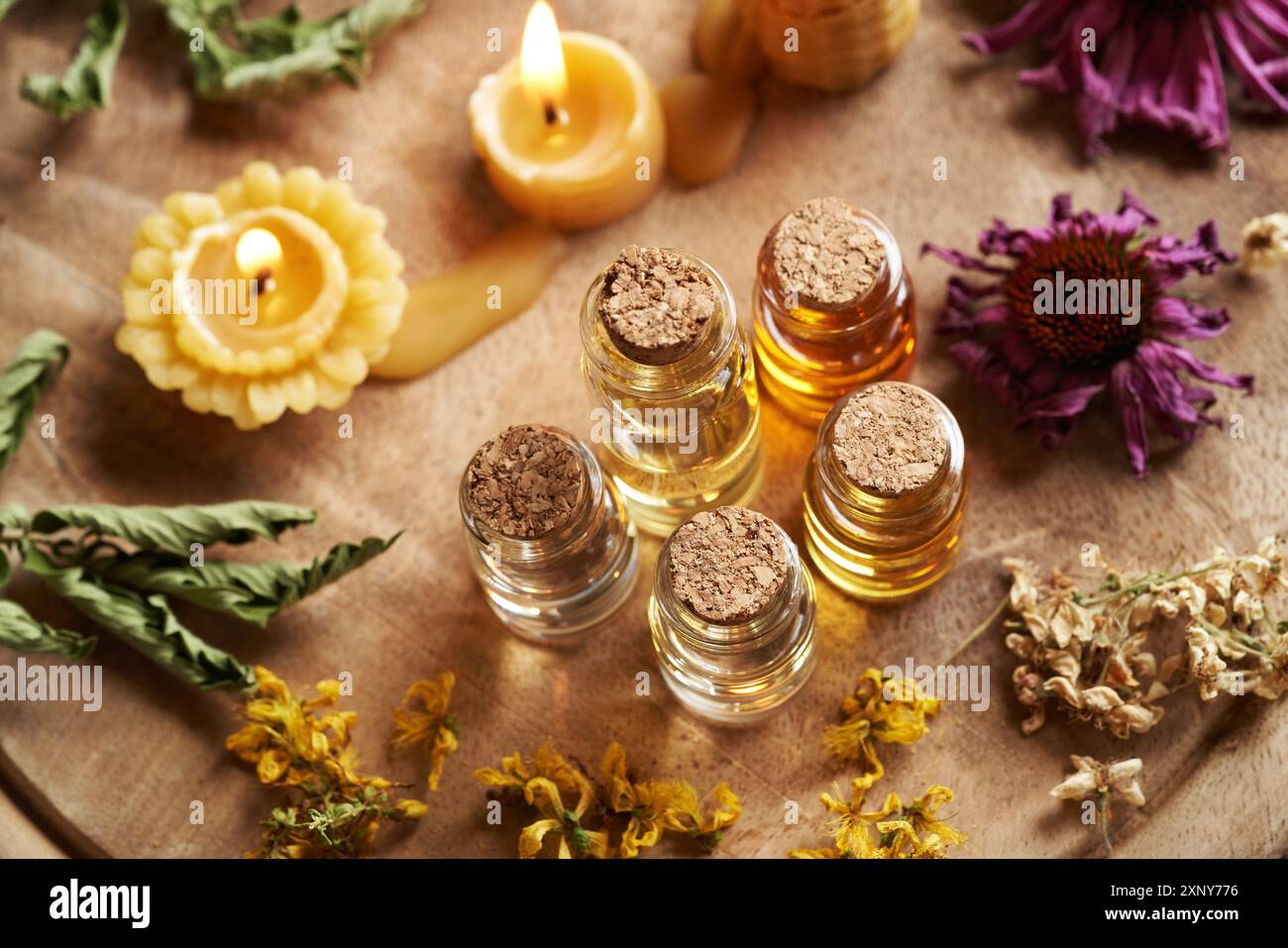 Bottiglie di oli essenziali con erbe secche e fiori e candele di cera d'api Foto Stock