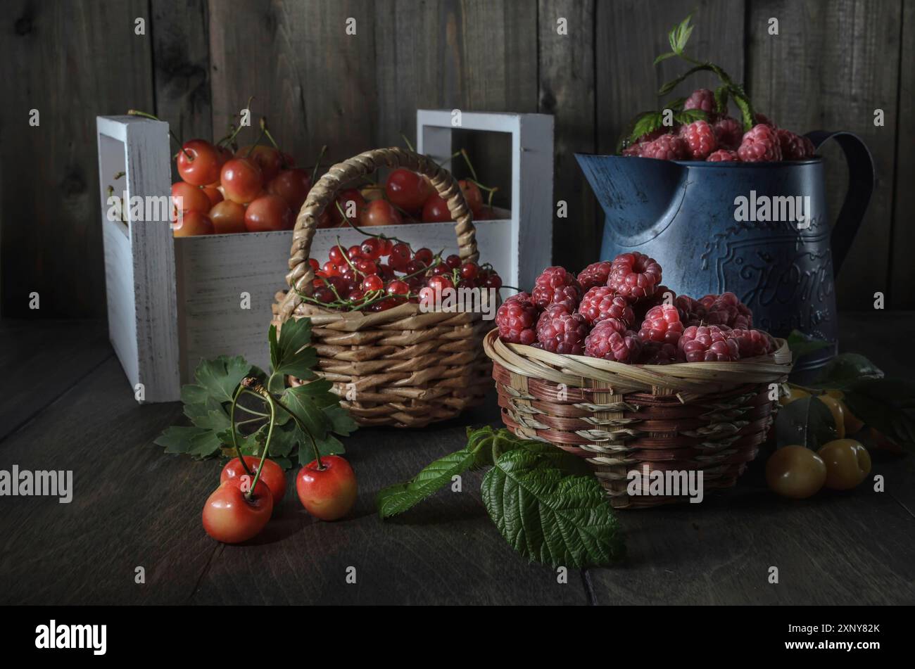 Raccolta di frutti di bosco maturi e succosi su sfondo di legno scuro in uno stile rustico Foto Stock