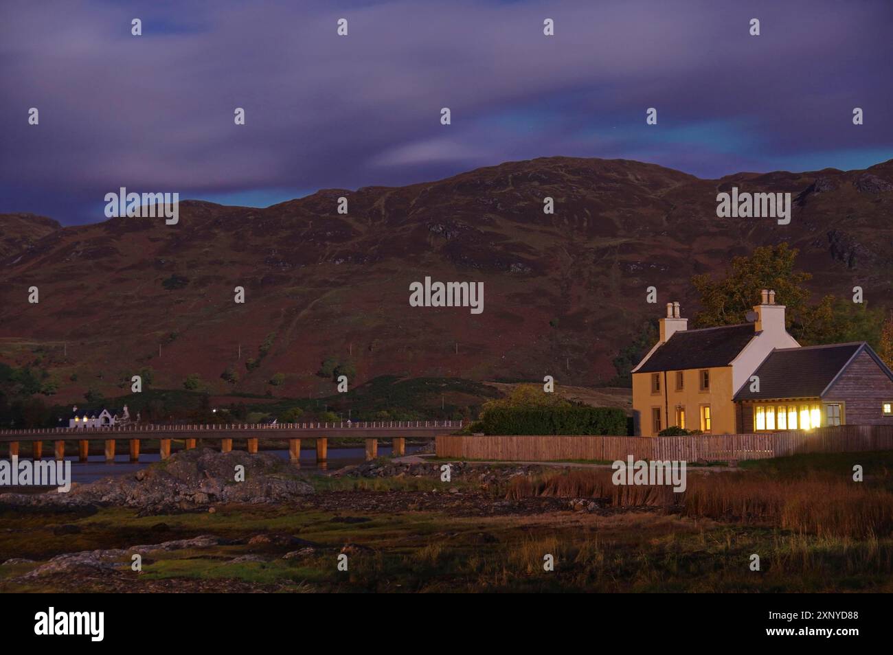 Casa illuminata in una zona remota su sfondo collinare di notte, Dornie, ottobre, Scozia, Regno Unito Foto Stock