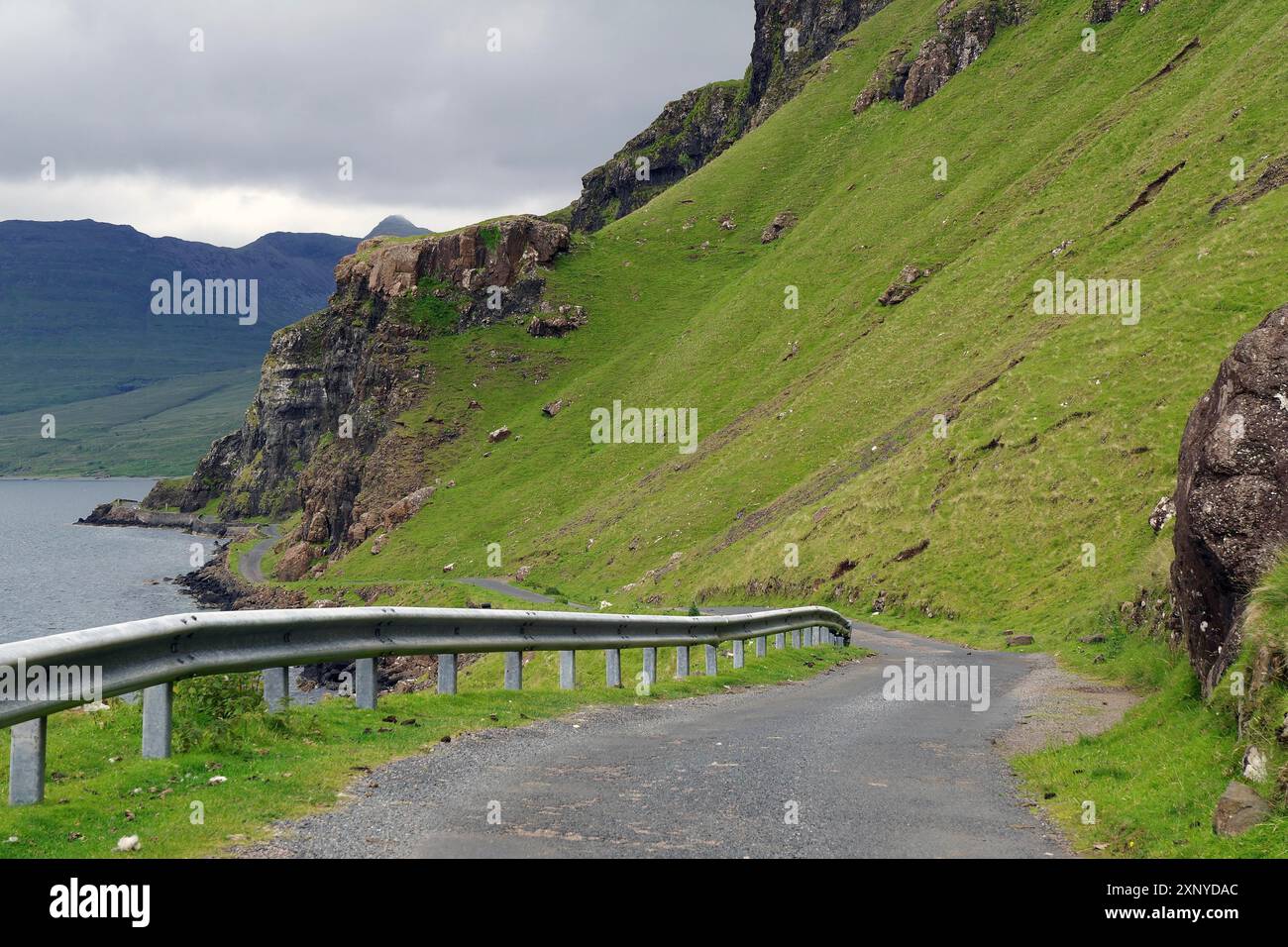 Una strada tortuosa lungo un verde paesaggio montano con vedute della costa, Mull, Ebridi interne, Scozia, Regno Unito Foto Stock