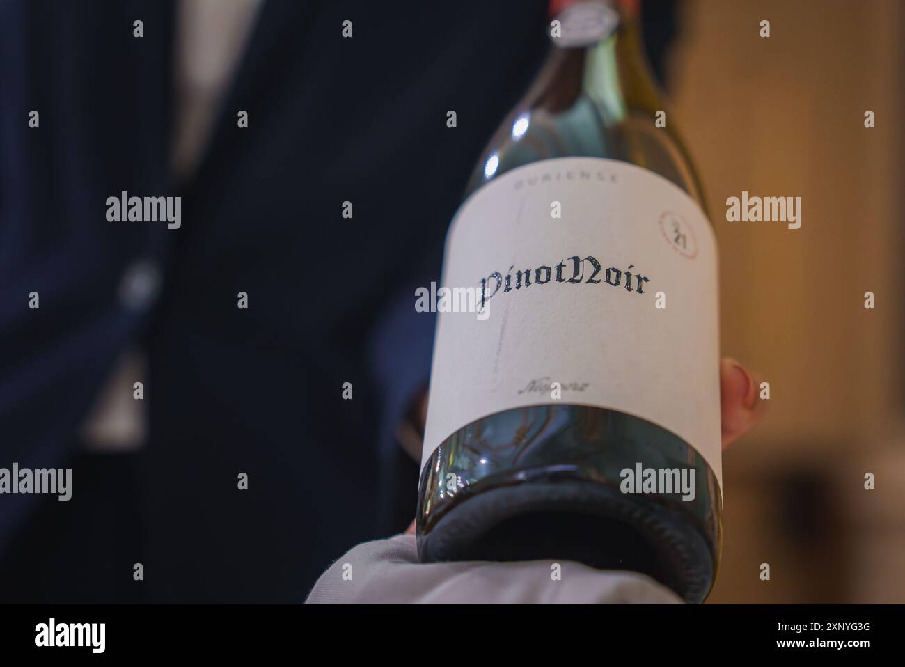 Primo piano della bottiglia di vino Pinot Nero presentata dal cameriere in un abbigliamento formale Foto Stock