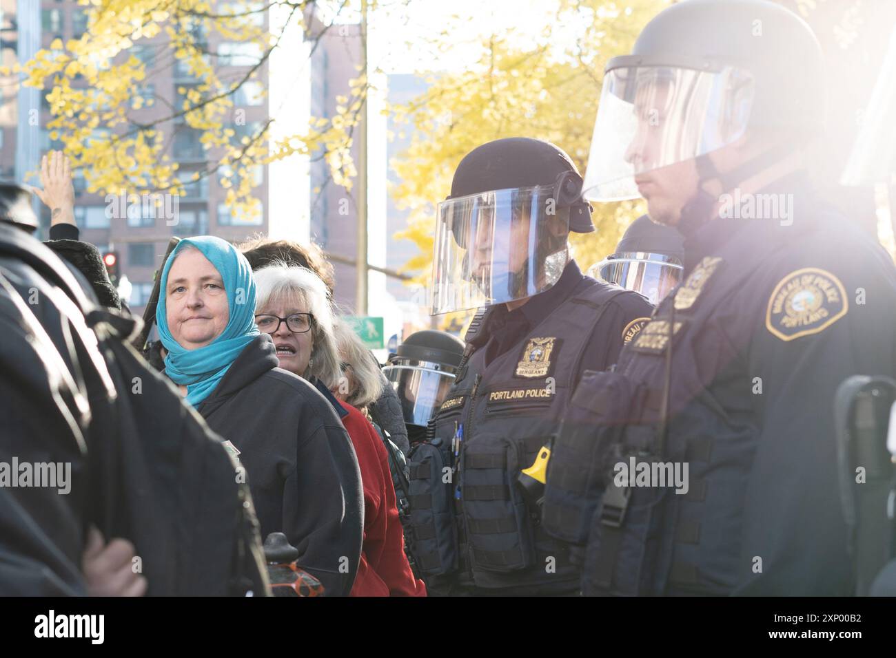 Due donne manifestanti circondate dalla polizia antisommossa guardano la telecamera di una protesta antifa contro i Proud Boys di Portland Foto Stock