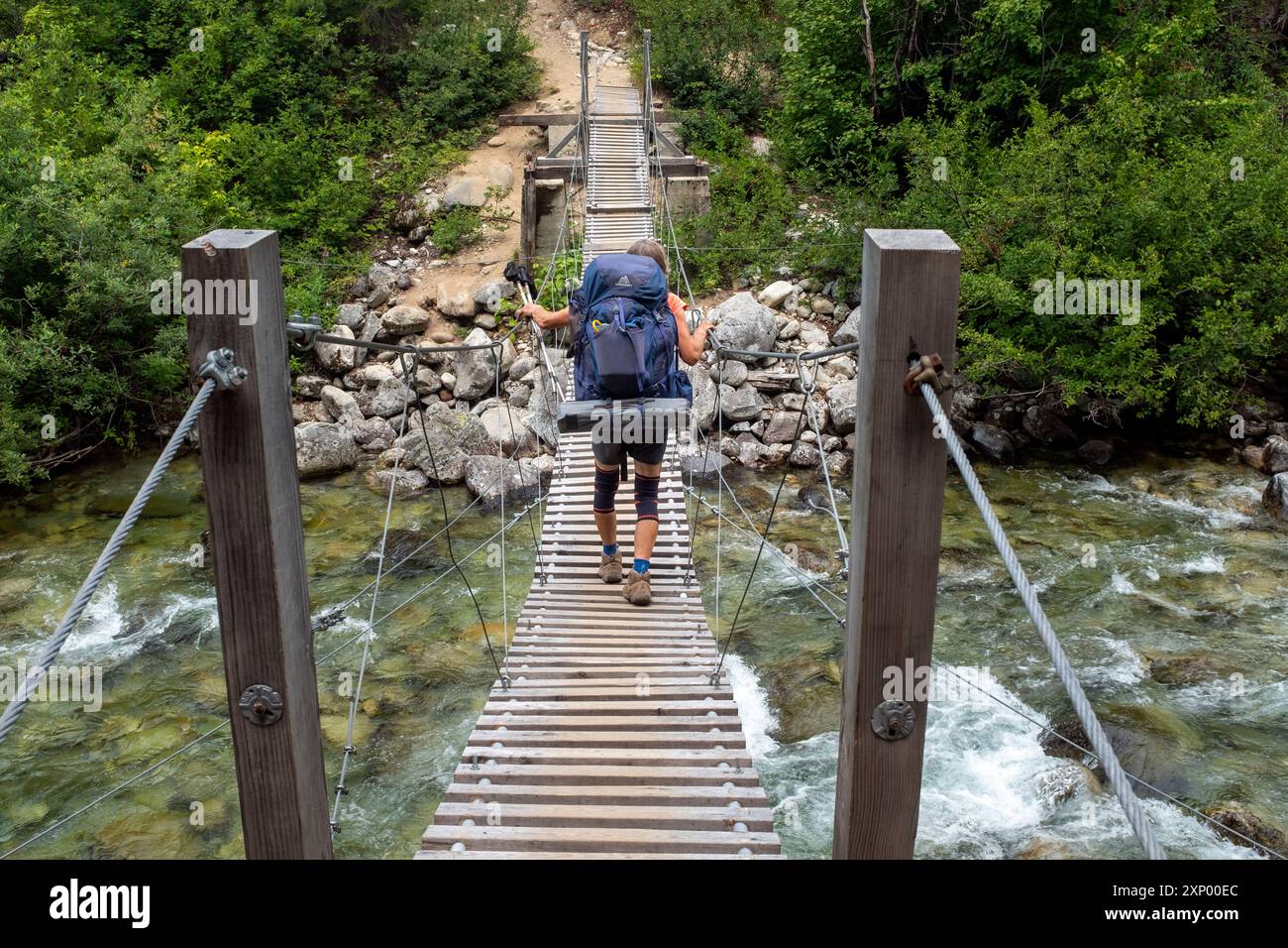 WA26012-00....WASHINGTON - donna che cammina lungo il Pacific Crest Trail attraversando Bridge Creek nel North Cascades National Park, Stephen Mather Wilderness. Foto Stock