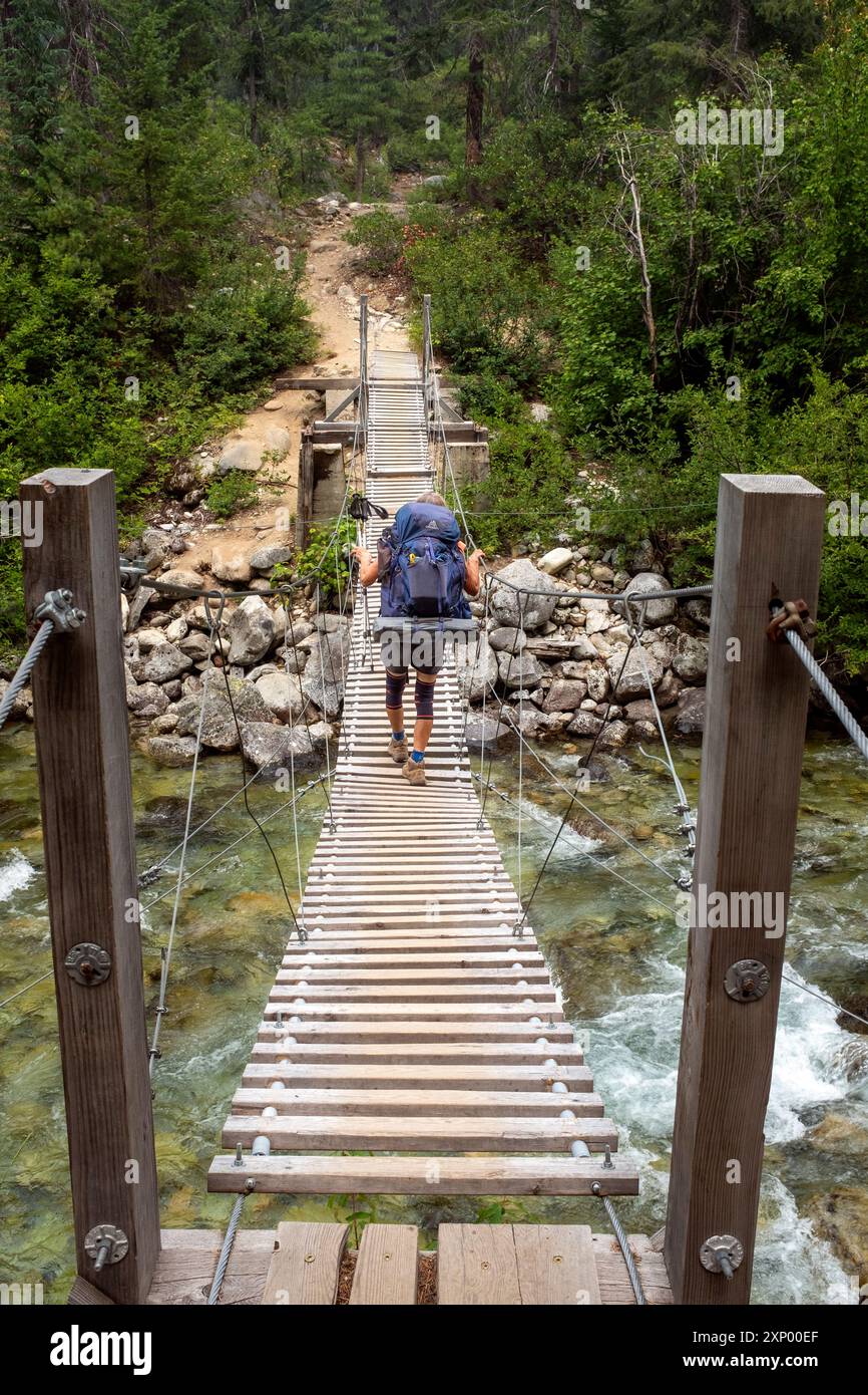 WA26013-00....WASHINGTON - donna che cammina lungo il Pacific Crest Trail attraversando Bridge Creek nel North Cascades National Park, Stephen Mather Wilderness. Foto Stock