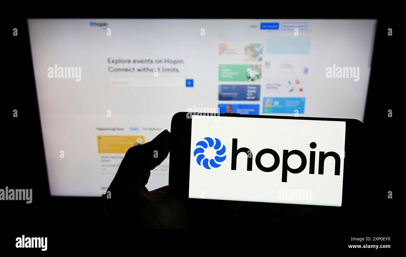 Stoccarda, Germania, 03-29-2022: Persona con smartphone con logo della società britannica di gestione eventi Hopin Ltd. Sullo schermo davanti al sito Web. Foto Stock