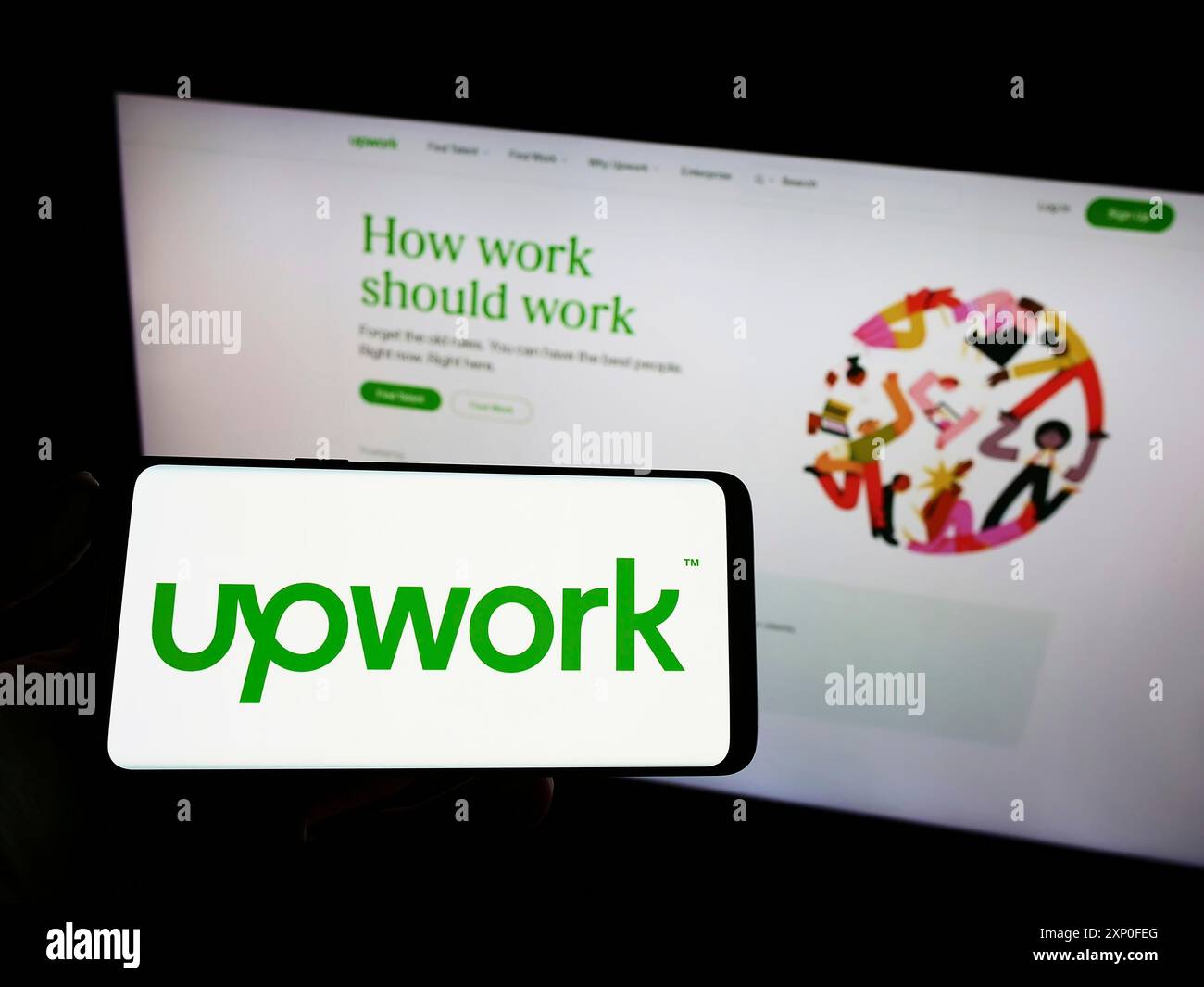 Stoccarda, Germania, 03-28-2022: Persona che tiene in mano uno smartphone con il logo della piattaforma di freelancing statunitense Upwork Global Inc. Sullo schermo davanti al sito Web. Foto Stock
