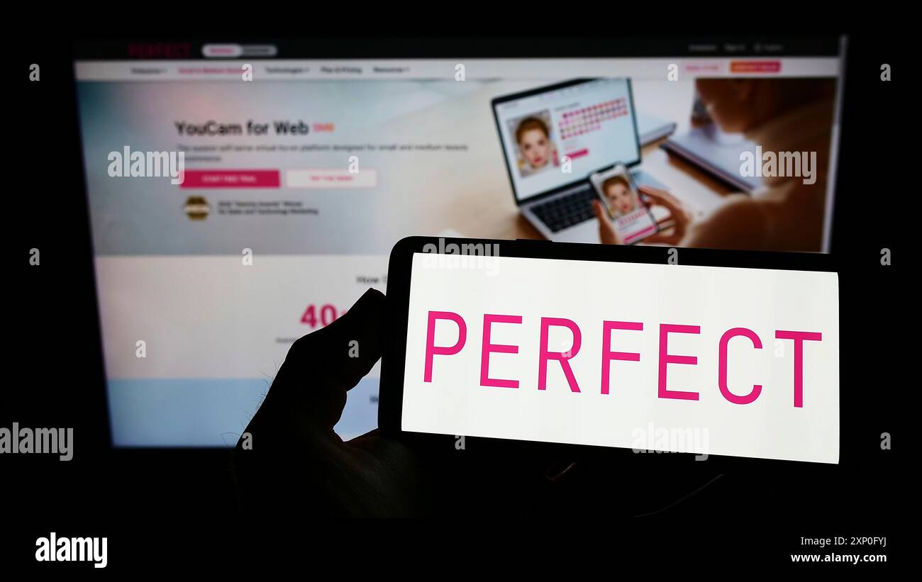 Stoccarda, Germania, 03-06-2022: Persona che tiene un telefono cellulare con il logo della società di bellezza taiwanese Perfect Corp. Sullo schermo di fronte alla pagina web. Foto Stock