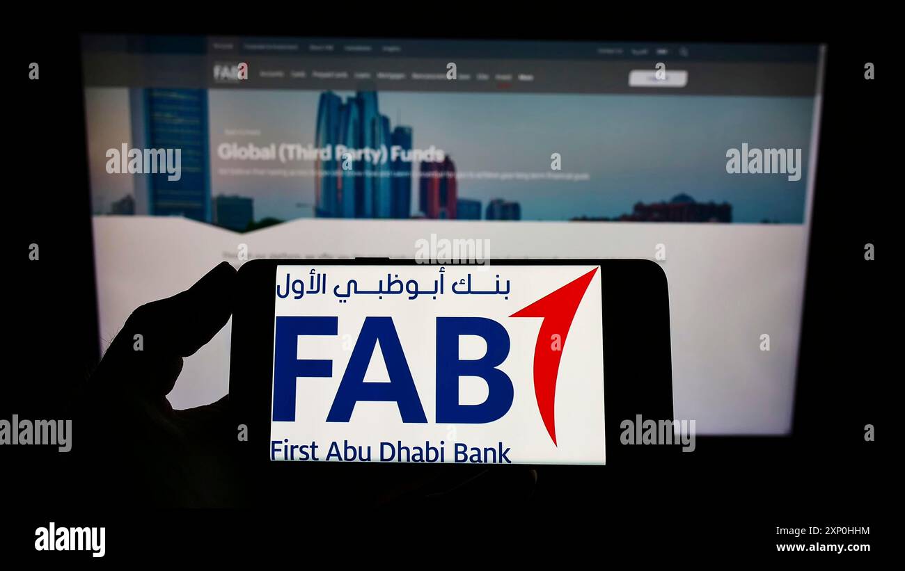 Stoccarda, Germania, 02-11-2022: Persona che detiene un telefono cellulare con il logo della società finanziaria First Abu Dhabi Bank (FAB) sullo schermo di fronte alla pagina web. Foto Stock