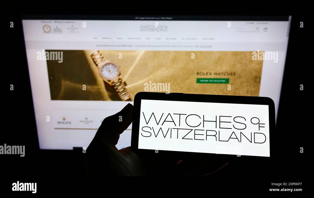 Stoccarda, Germania, 01-16-2022: Persona con smartphone con logo del rivenditore britannico Watches of Switzerland Group PLC sullo schermo di fronte Foto Stock