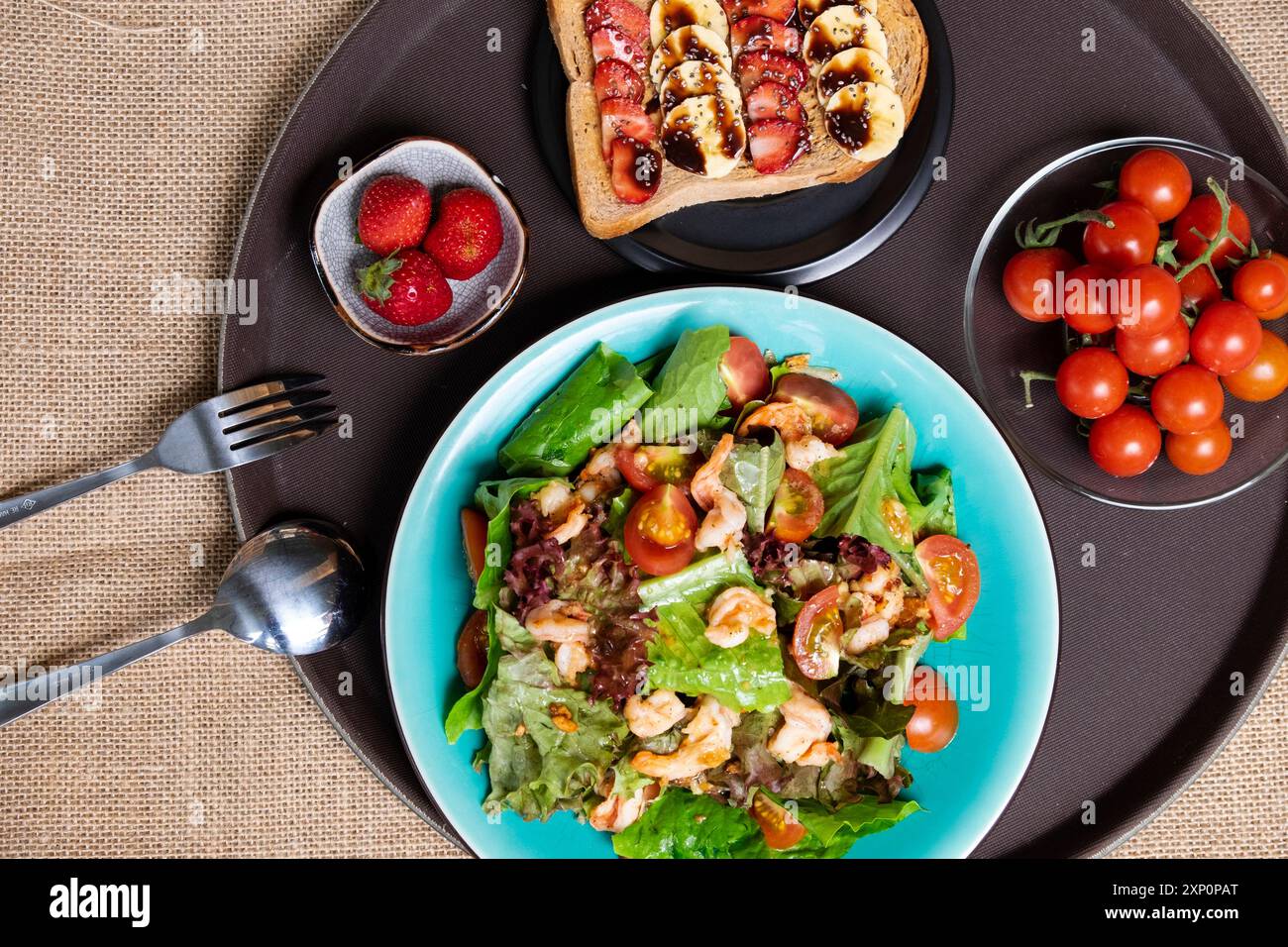 Una colazione vivace e allettante con insalata colorata, gamberi, pomodori maturi, sandwich, banane, fragole fresche. Un pasto salutare offre un delizioso nutri Foto Stock