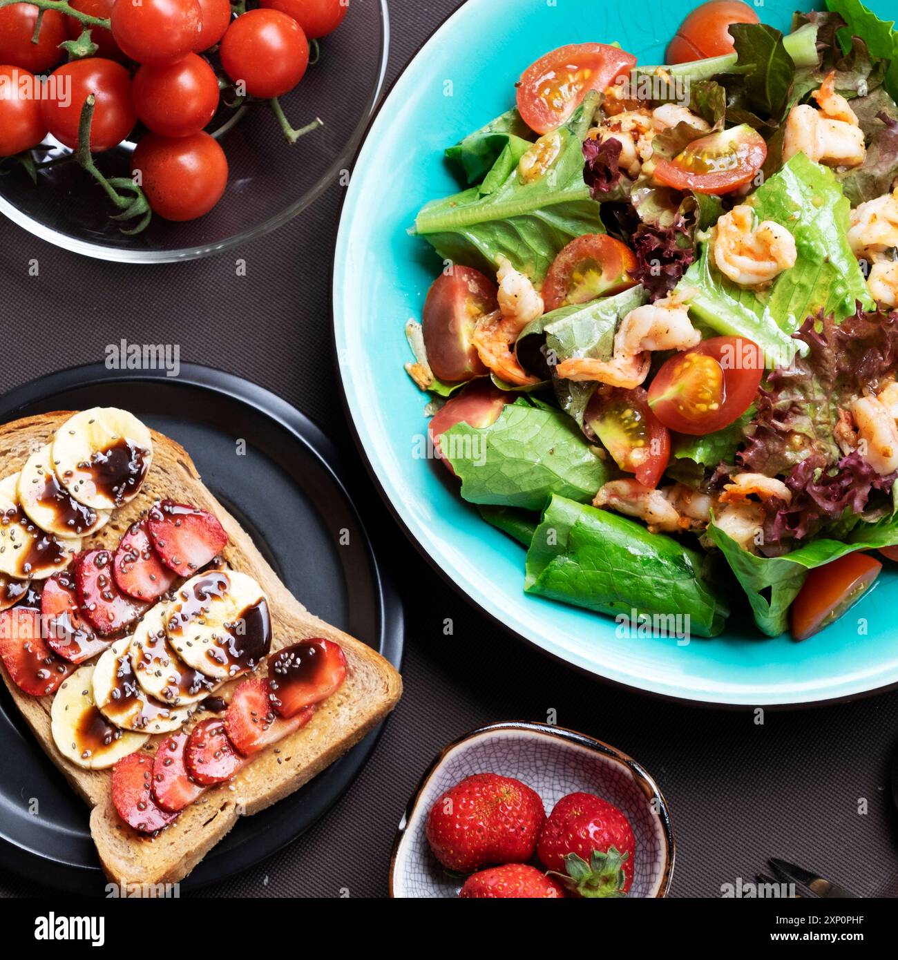 Una colazione vivace e allettante con insalata colorata, gamberi, pomodori maturi, sandwich, banane, fragole fresche. Un pasto salutare offre un delizioso nutri Foto Stock
