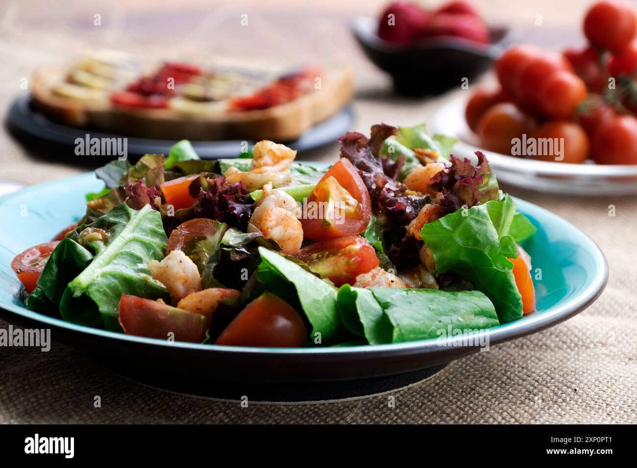 Una colazione vivace e allettante con insalata colorata, gamberi, pomodori maturi, sandwich, banane, fragole fresche. Un pasto salutare offre un delizioso nutri Foto Stock