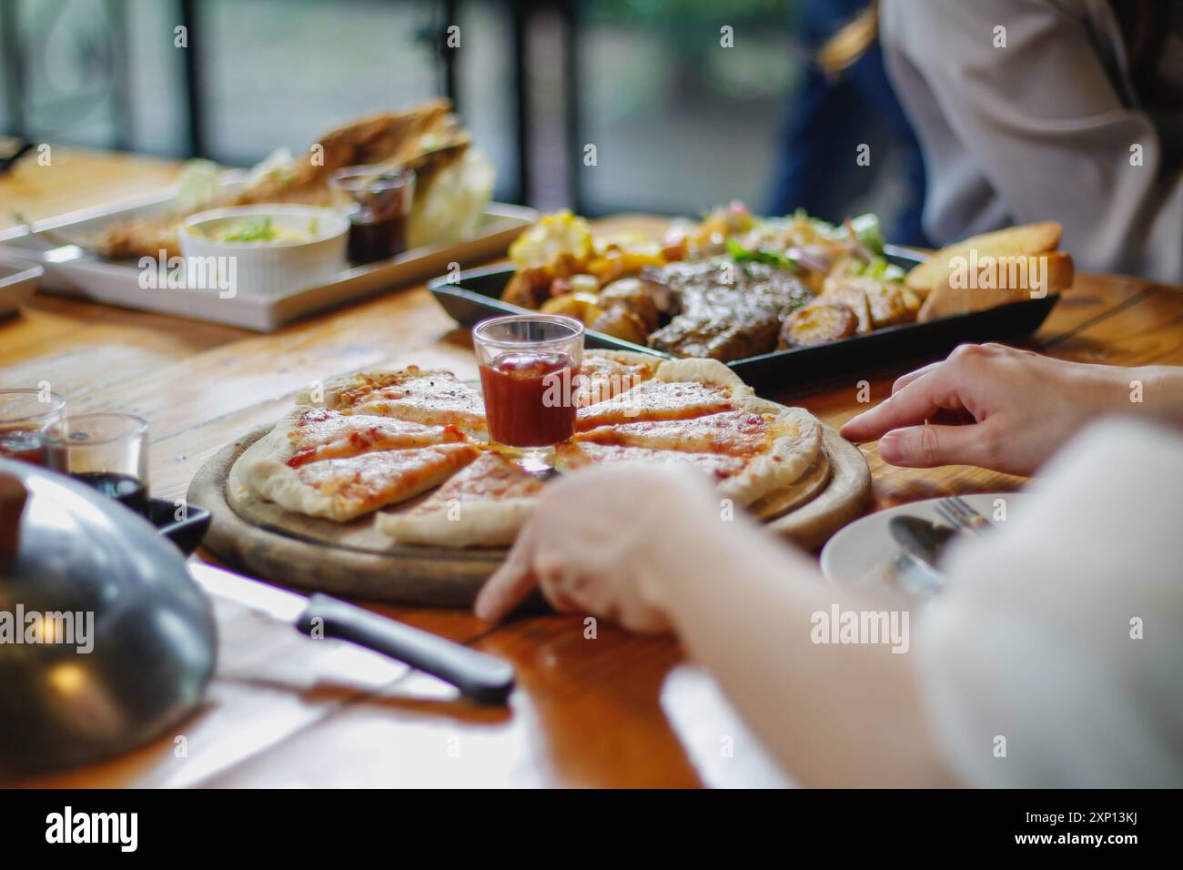 Una giovane donna è felice di vedere il cibo sul tavolo e scegliere il menu della pizza da mangiare con buon gusto. I menu di pizza sono perfetti per banchetti tra frien Foto Stock Una giovane donna è felice di vedere il cibo sul tavolo e scegliere il menu della pizza da mangiare con buon gusto. I menu di pizza sono perfetti per banchetti tra frien Foto Stock