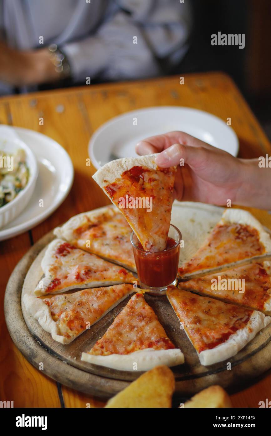 Una giovane donna è felice di vedere il cibo sul tavolo e scegliere il menu della pizza da mangiare con buon gusto. I menu di pizza sono perfetti per banchetti tra frien Foto Stock