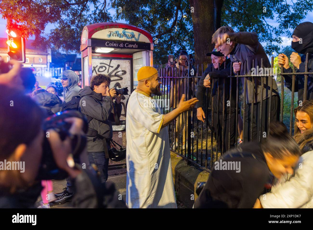 Liverpool, Regno Unito. 02 AGOSTO 2024. Un imam della moschea Abdullah Quiliam attraversa la strada per parlare con i manifestanti del lato opposto. I manifestanti che si identificano come ala destra, così come i membri del SUTR e le organizzazioni di sinistra si sono riuniti sui lati opposti della strada fuori dalla moschea di Abdullah Quilliam, una delle prime moschee in Inghilterra, in uno sfondo di rivolte in tutto il paese a seguito di un incidente a Southport. A parte alcune urla e alcuni manifestanti che hanno attraversato brevemente i lati, non si sono osservati problemi. Credito Milo Chandler/Alamy Live News Foto Stock