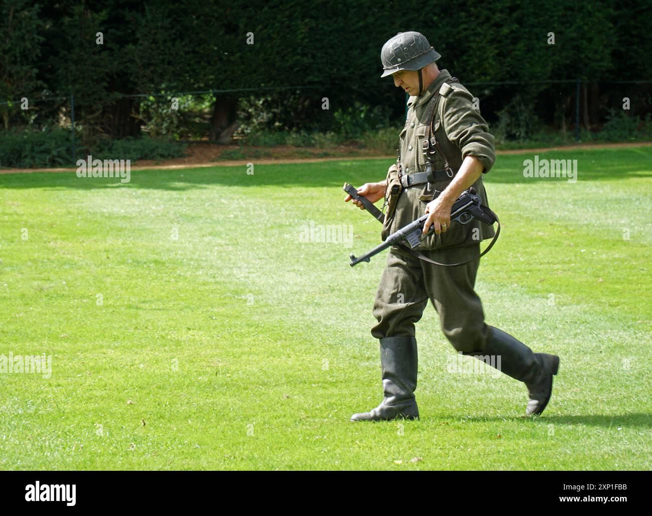 Uomo che cammina in uniforme tedesca della seconda guerra mondiale con . Mitragliatrice Schmeisser Foto Stock