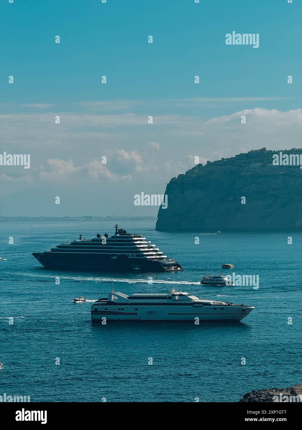 Una grande nave sta navigando nell'oceano accanto a una nave più piccola. Il cielo è limpido e l'acqua è calma Foto Stock