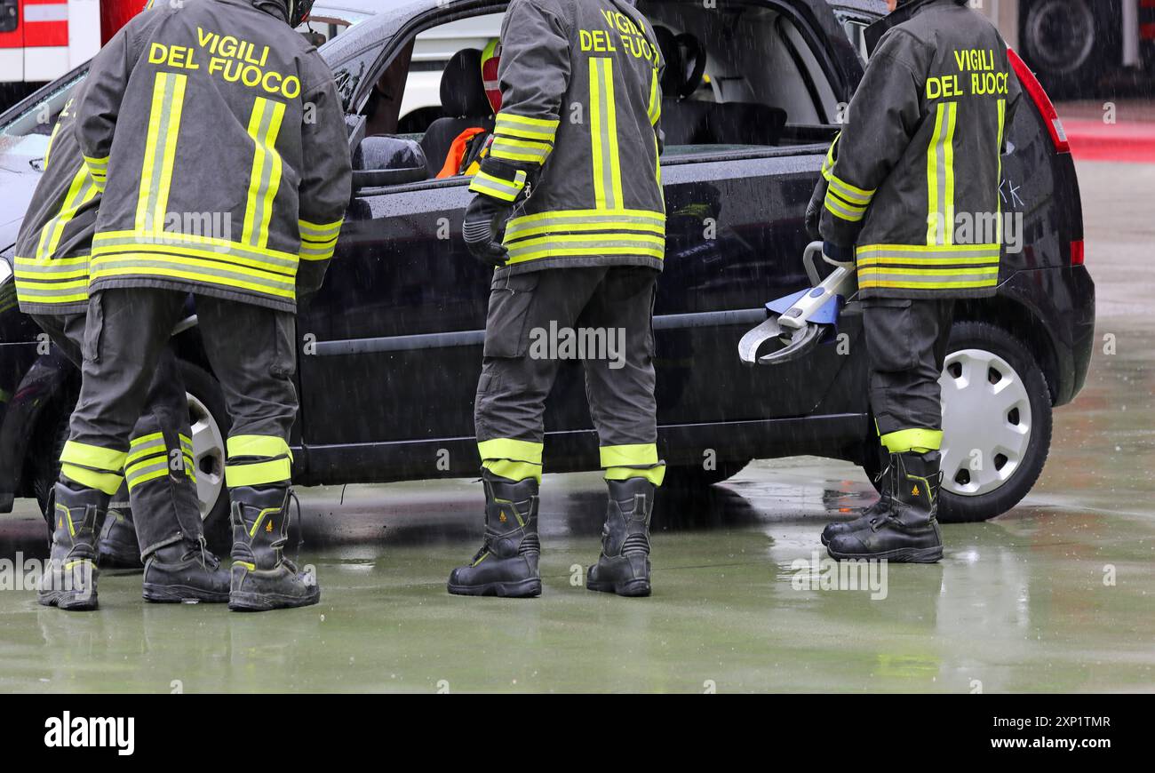 Vicenza, vi, Italia - 30 maggio 2024: Vigili del fuoco italiani con cesoie per aprire la porta dell'auto dopo un incidente stradale durante la pioggia Foto Stock