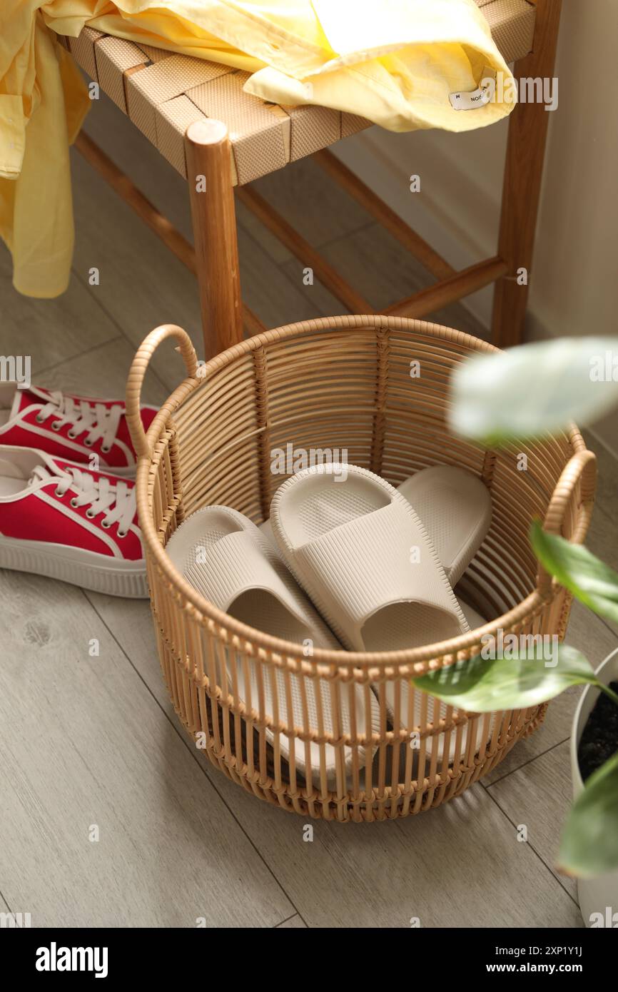 Cestino con pantofole per gli ospiti e scarpe da ginnastica all'ingresso di casa Foto Stock