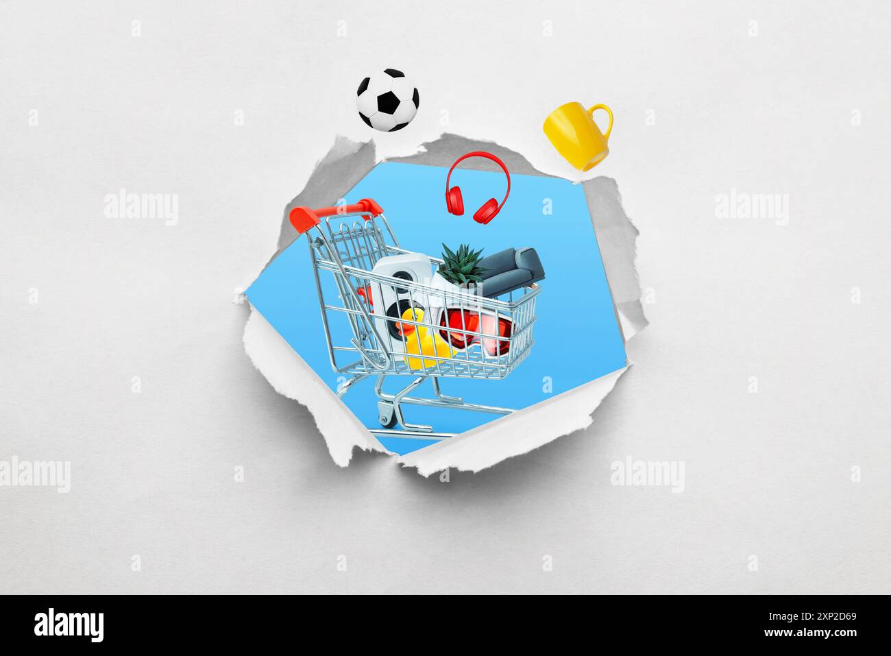 Buco strappato nella carta con un carrello pieno di prodotti emergenti. Concetto di shopping e acquisto di vari articoli attraverso una prospettiva creativa Foto Stock