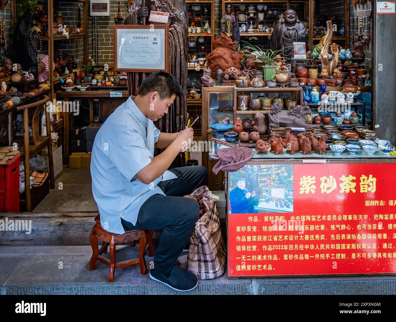 Un uomo che fa artigianato con l'argilla davanti a un negozio. Chengdu, Sichuan, Cina. Foto Stock