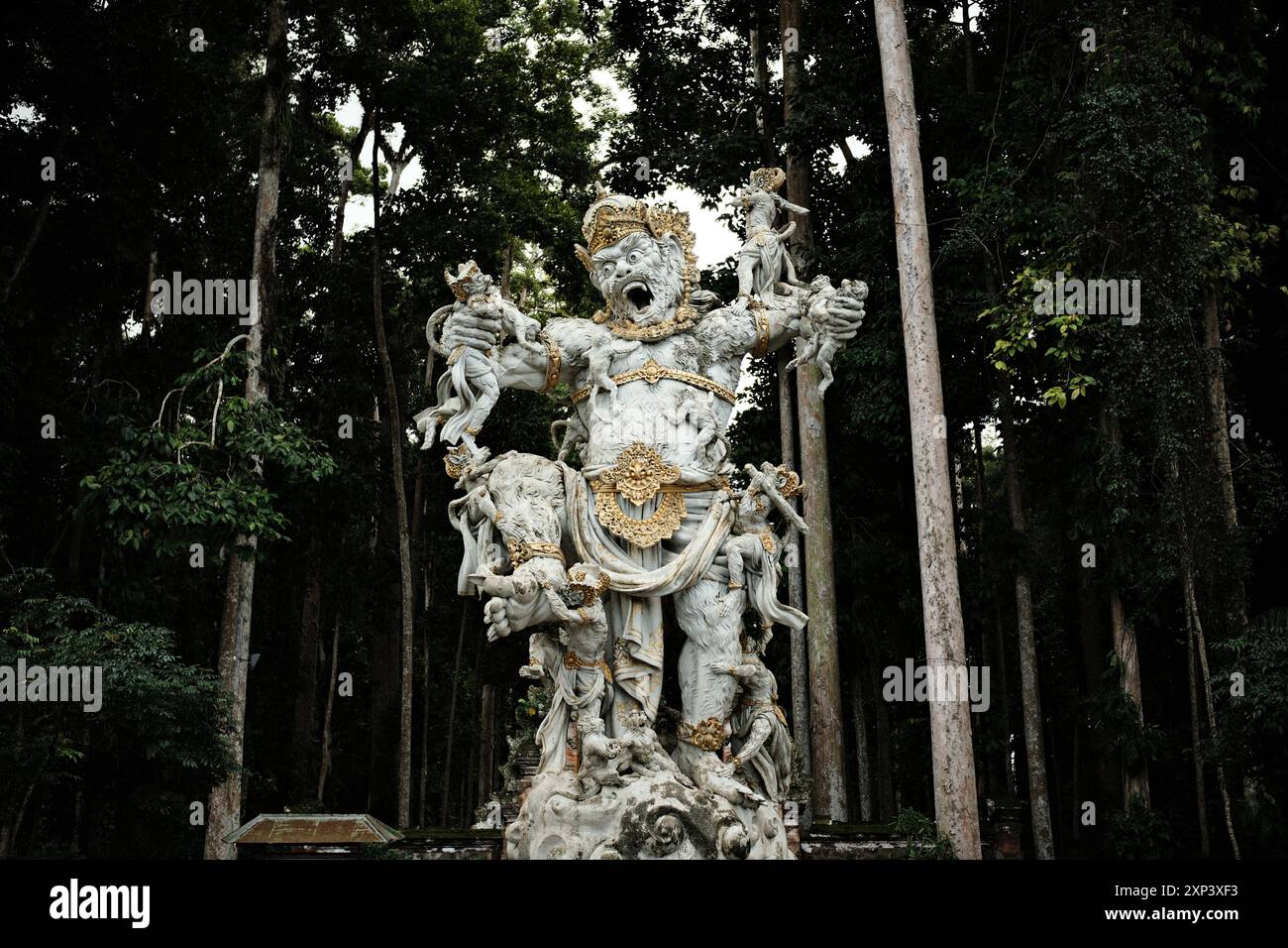 Ubud, Bali, Indonesia - 9 luglio 2024: Monumento culturale ed etnico balinese con statua in giardino su uno sfondo scuro della foresta Foto Stock