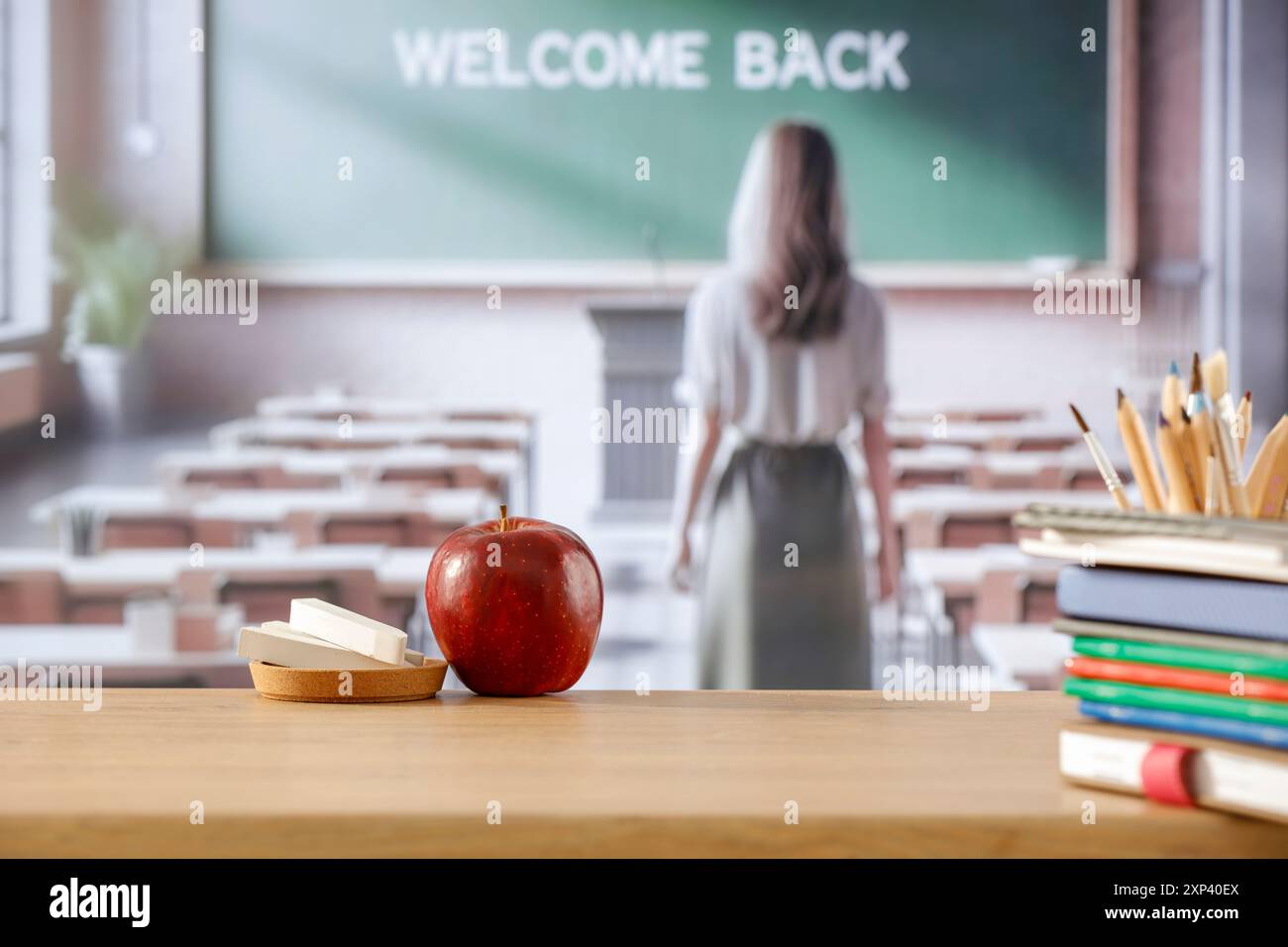 Scrivania in legno e insegnante donna all'interno dell'aula. Sfondo del tavolo scolastico con spazio di copia per le forniture scolastiche e altri prodotti montaggio dsiplay. Foto Stock