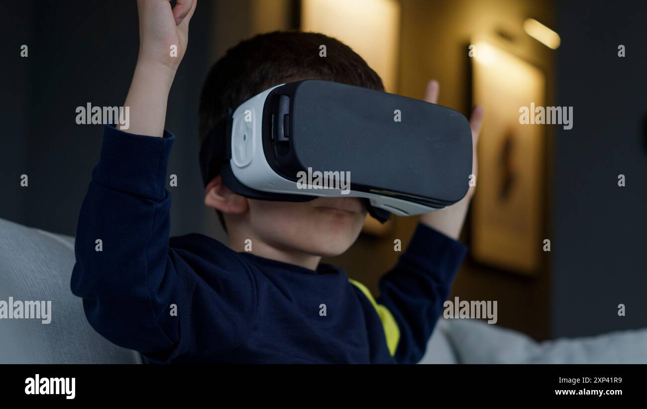 Un ragazzo che esplora la realtà virtuale con un visore VR. Il fascino e la natura interattiva della tecnologia moderna per i bambini. Foto Stock