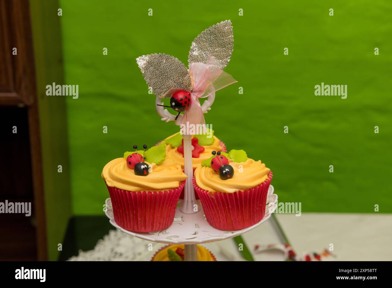 Cupcake con decorazioni di coccinelle sul supporto per torte su sfondo verde brillante Foto Stock