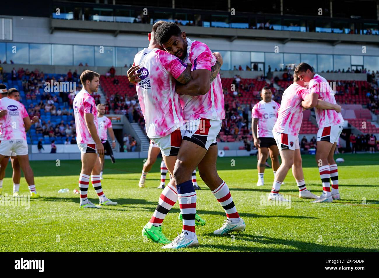 Salford, Manchester, Regno Unito. 3 agosto 2024. Super League Rugby: Salford Red Devils vs Leeds Rhinos al Salford Community Stadium. Salford si riscalda con le maglie da allenamento Cancer Research prima del loro gioco contro i Leeds Rhinos. Credito James Giblin/Alamy Live News. Foto Stock