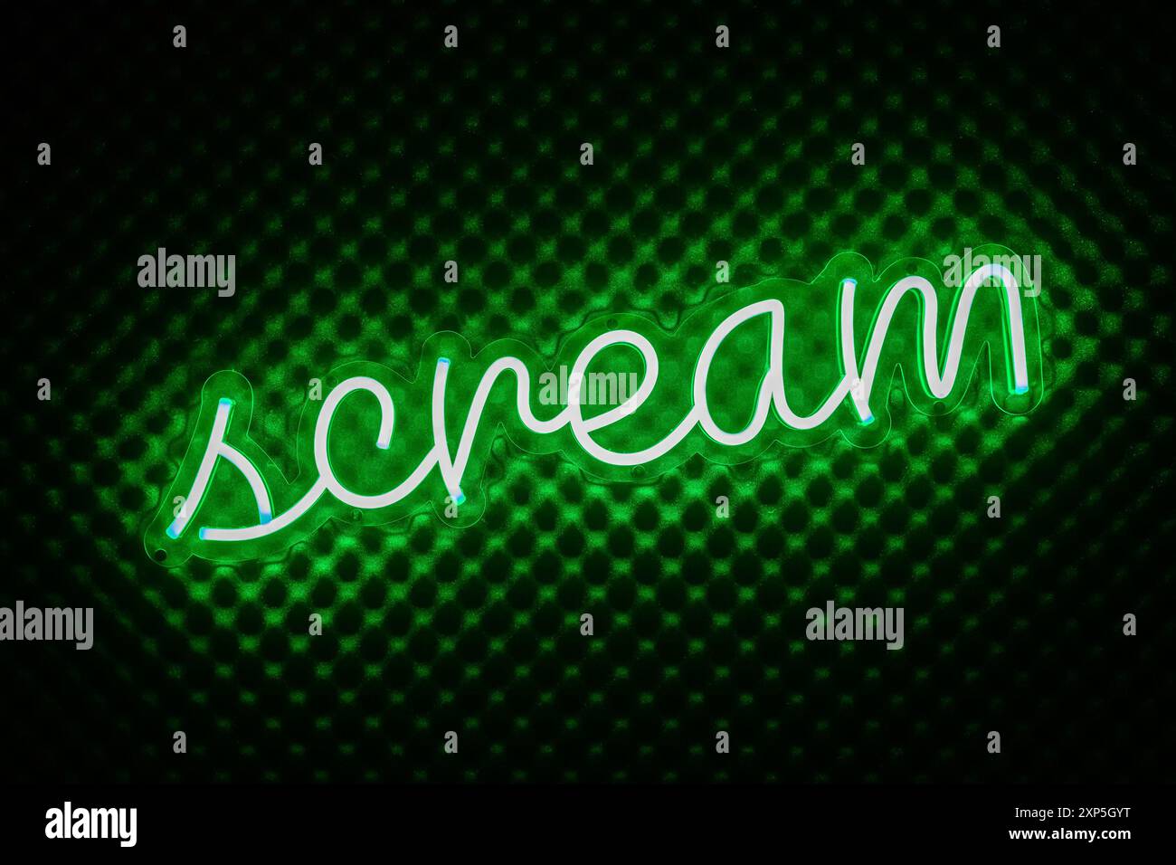 Insegna al neon con scritta urla di colore verde. Contorno della parola grida con luce verde o bagliore, su un materiale simile alla schiuma che suprime il suono del grigio scuro Foto Stock