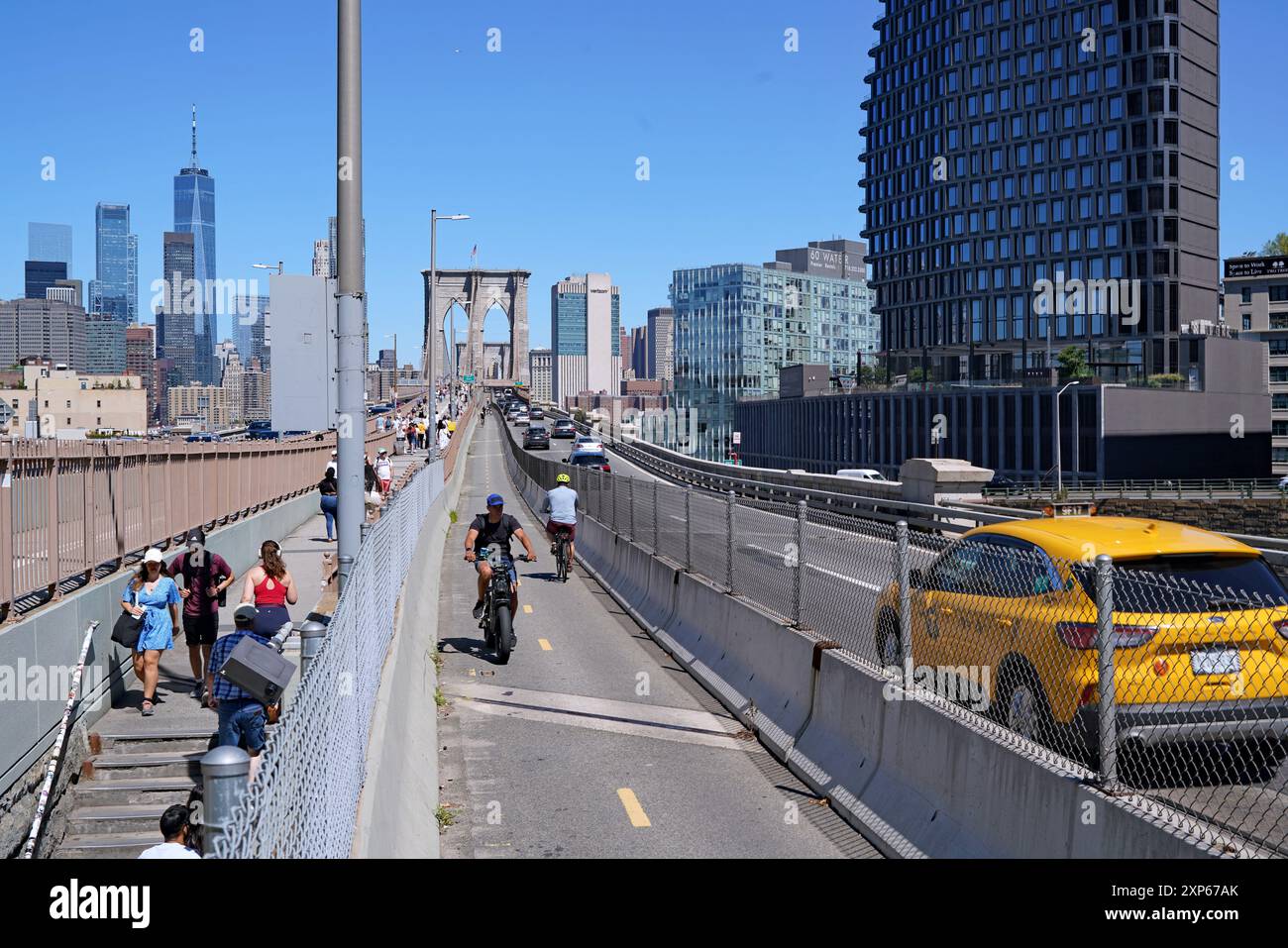 Persone che attraversano le piste pedonali e ciclabili del Ponte di Brooklyn Foto Stock