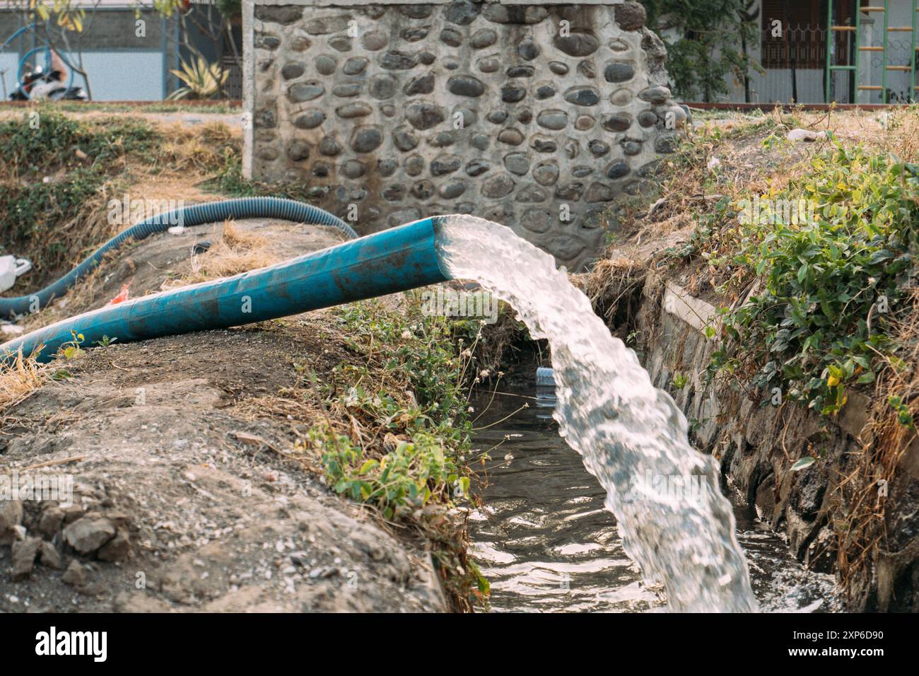 Un tubo blu sta pompando l'acqua in un fosso Foto Stock