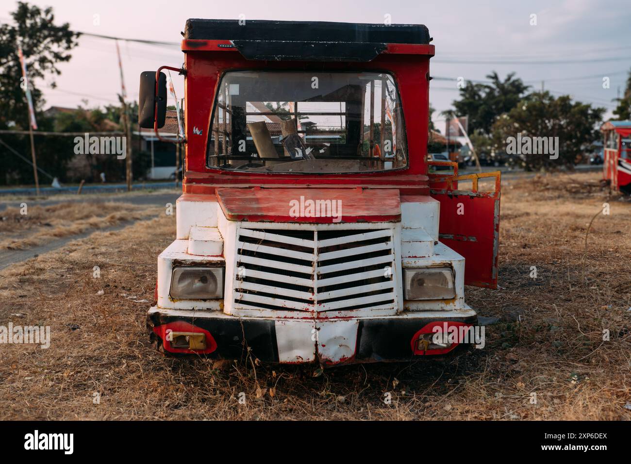 Un autobus rosso e bianco parcheggiato su una strada sterrata Foto Stock