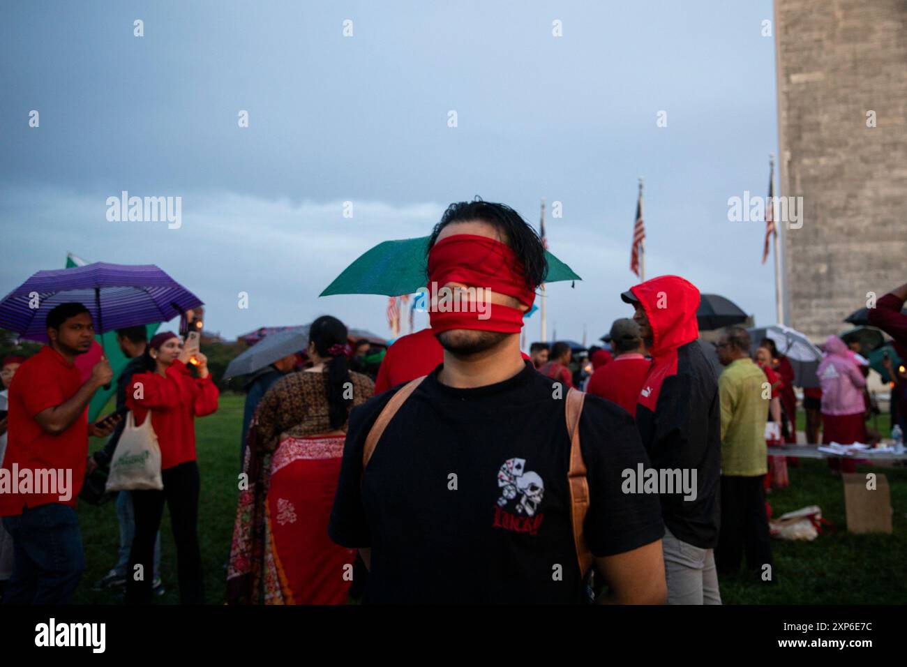 Washington DC, Stati Uniti. 3 agosto 2024. Un partecipante lega un panno rosso sulla bocca e sugli occhi mentre assiste a una veglia a lume di candela il 3 agosto 2024 al National Mall, Washington DC, USA, per sostenere il movimento anti-discriminatorio degli studenti in Bangladesh. Nella veglia, i partecipanti hanno condannato il governo per aver ucciso studenti innocenti e minorenni. Chiedono anche di dimettersi dall'attuale primo ministro Sheikh Hasina, che è al potere dal 2009. Ma le proteste successive sono iniziate con spargimenti di sangue, e più di 250 persone sono state uccise. Credito: Aashish credito: Aashish Kiphayet/Alamy Live News Foto Stock