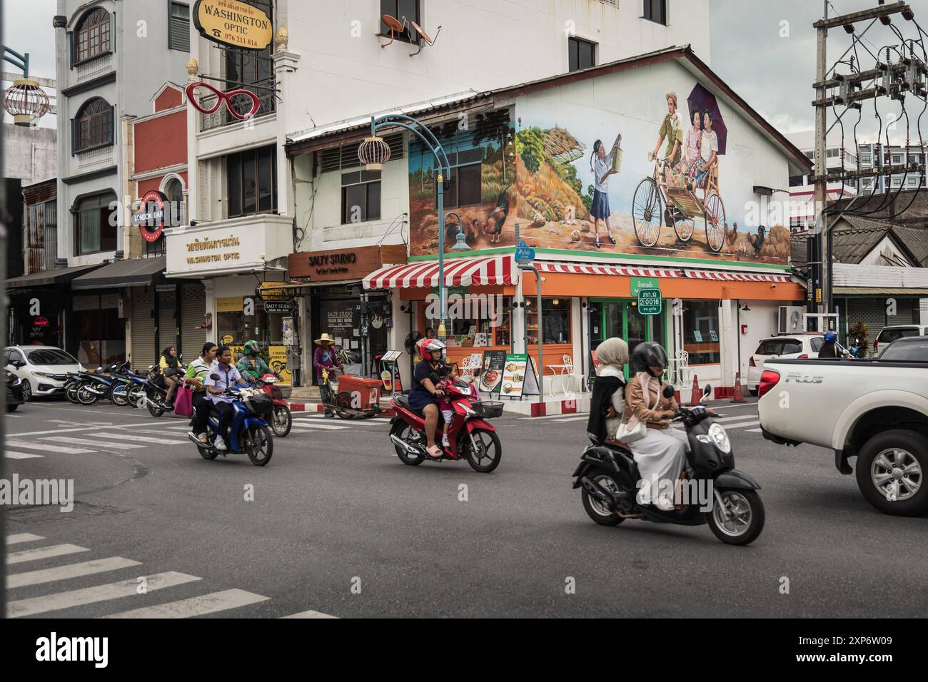 Vista del centro di Phuket in Thailandia con moto e auto sulla strada. Strada trafficata con ristoranti e negozi. Destinazione del viaggio. Foto di strada. Foto Stock