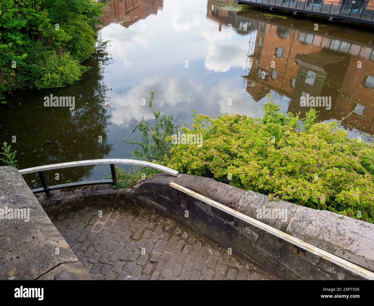 Wigan Pier Regno Unito. Vista panoramica di un tranquillo canale urbano con riflessi di edifici e vegetazione lungo la riva. Foto Stock