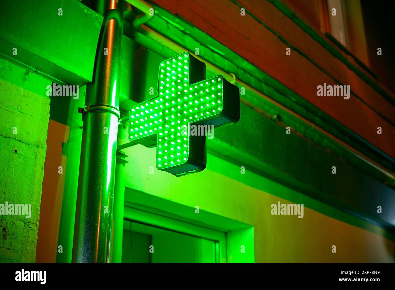 Croce verde luminosa di notte come segno della farmacia Foto Stock