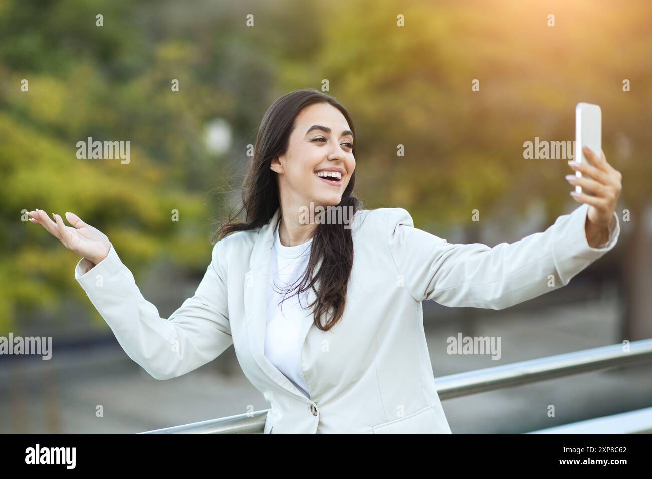 Donna sorridente che porta Selfie con smartphone su City Street Foto Stock