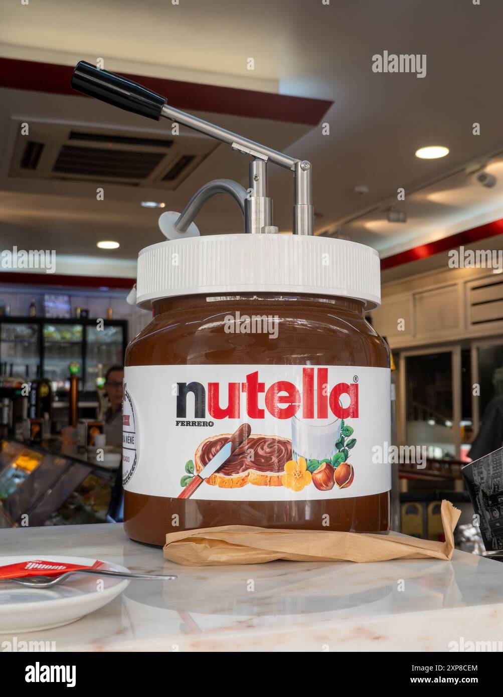 Giant Jar of Nutella con erogatore a pompa riscaldato in Un caffè di Lisbona, usato per versare la Nutella sui dessert crema di nocciole il 16 aprile 2024 Foto Stock