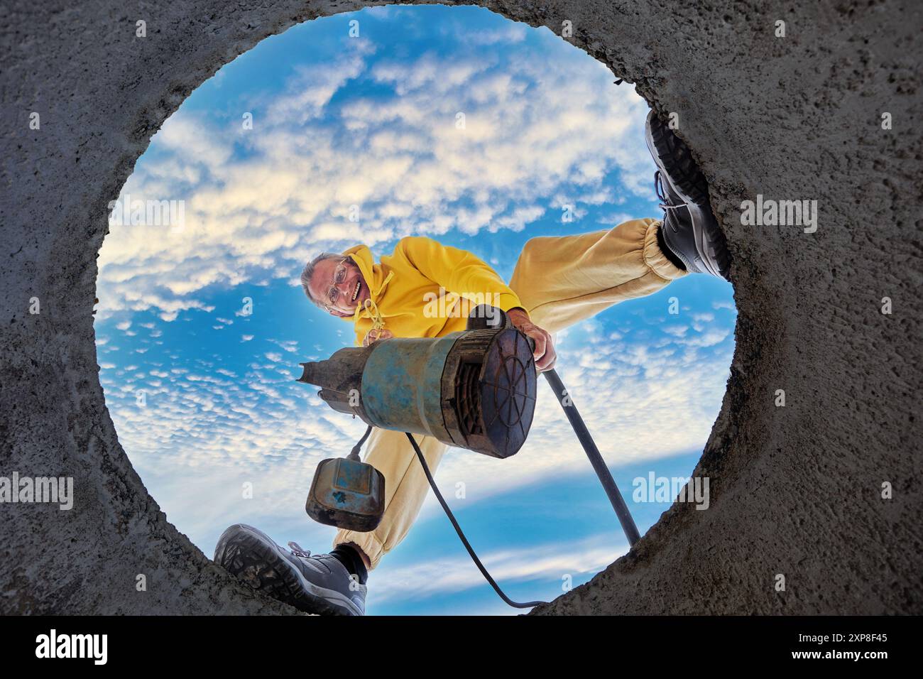 Vista dal basso dell'uomo che immerge la pompa per acque reflue nel serbatoio settico. Foto Stock