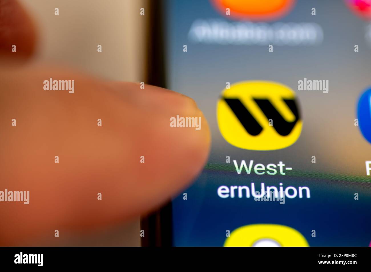 Londra. REGNO UNITO- 07.28.2024. Servizi finanziari americani, app per il trasferimento di denaro Western Union sullo schermo di un telefono cellulare con un dito rivolto verso di esso Foto Stock